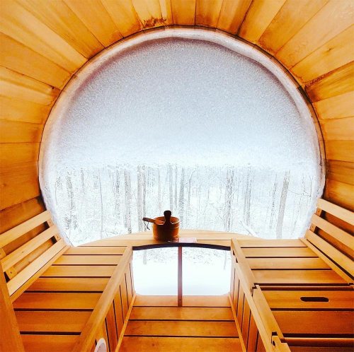 Cozy wooden sauna interior with a snow-covered window view of a winter landscape.