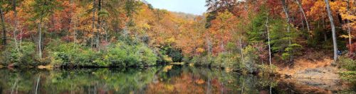 A serene lake surrounded by vibrant autumn foliage reflecting in the water.