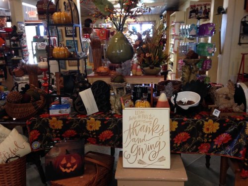 A cozy shop display featuring autumn decorations, pumpkins, and a sign that reads "Thanks and Giving."