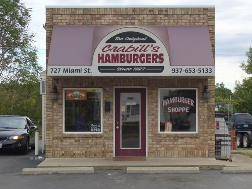Exterior of Crabill's Hamburgers, a brick building with a purple awning, sign, and open door, located at 727 Miami St.