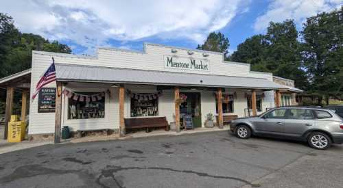 A quaint market building with an American flag, surrounded by trees and a parked car in the foreground.