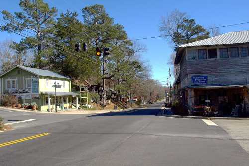 A quiet street scene with a traffic light, featuring quaint buildings and trees under a clear blue sky.