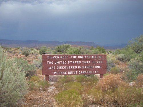Sign in a desert landscape reads: "Silver Reef - The only place in the U.S. where silver was discovered in sandstone. Drive carefully."