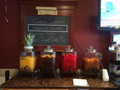 Four glass dispensers filled with colorful beverages, alongside a chalkboard listing today's specials.