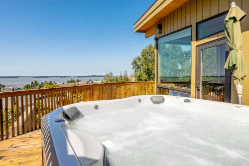 A hot tub on a wooden deck with a scenic view of a lake and clear blue sky in the background.