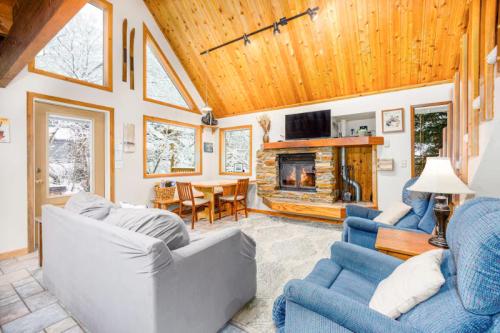 Cozy living room with a stone fireplace, wooden ceiling, and large windows overlooking a snowy landscape.