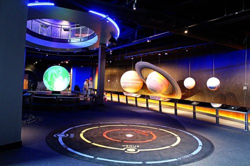 A planetarium exhibit featuring large models of planets and a circular floor display labeled "Venus."