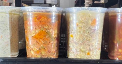 Two clear containers filled with colorful soups or stews, showcasing various vegetables and ingredients.