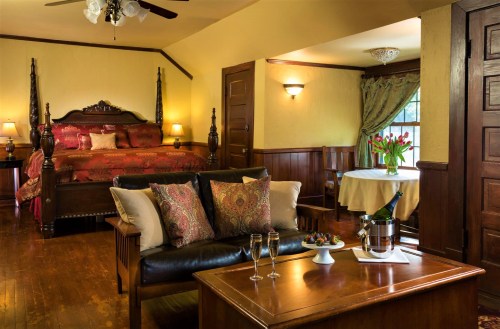 Cozy room with a king bed, seating area, and dining table, featuring warm colors and elegant decor.