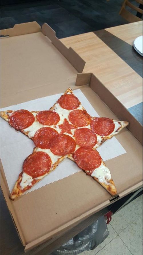 A star-shaped pizza with pepperoni slices, placed in an open pizza box on a table.