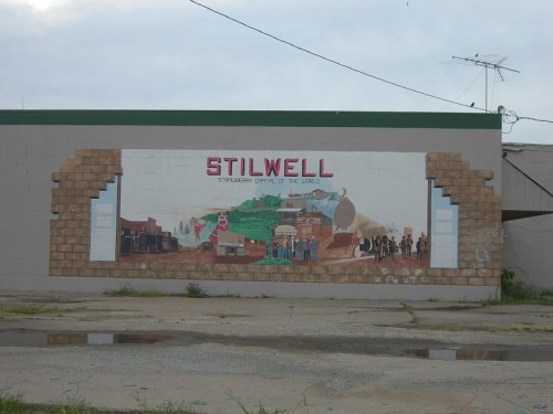 Mural on a building in Stilwell, depicting local history and culture with the text "Stilwell Strawberry Capital of the World."