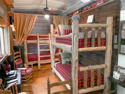 Cozy cabin-style room with two sets of wooden bunk beds, plaid bedding, and rustic decor.