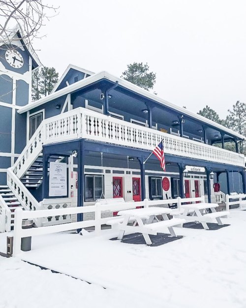 A blue building with white trim and an American flag, surrounded by snow and featuring a clock tower.