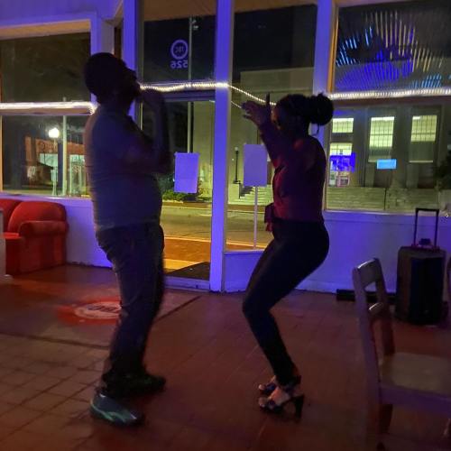 A man and woman dance together in a dimly lit venue, enjoying a lively moment.