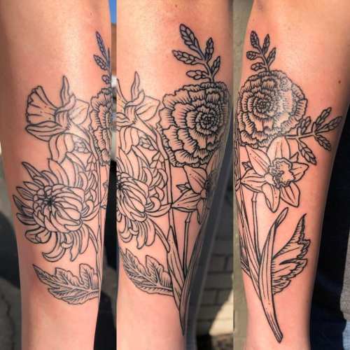 A close-up of a detailed floral tattoo featuring various flowers on a person's forearm.
