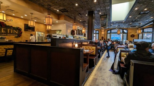 A bustling restaurant interior with wooden booths, warm lighting, and diners enjoying their meals.