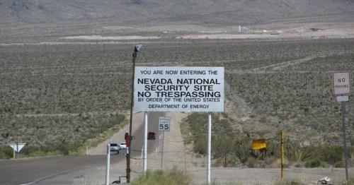 White sign indicating the Nevada Test Site in a rural, remote area of Nevada.