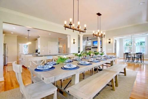 A spacious dining area with a large wooden table set for dinner, surrounded by modern decor and bright natural light.