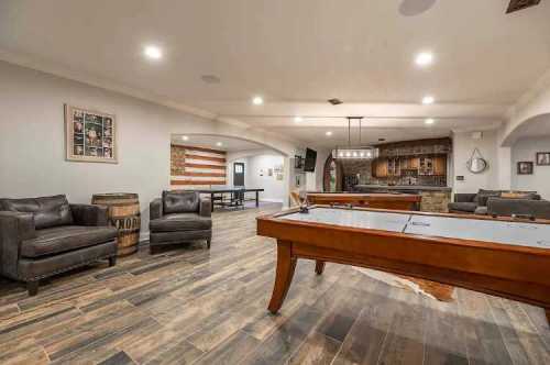 A spacious game room featuring a pool table, seating area, and a rustic bar with an American flag decor.