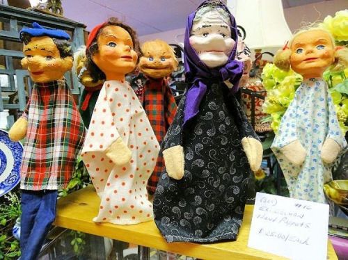 A display of colorful vintage puppets in various outfits, showcasing different characters and expressions.
