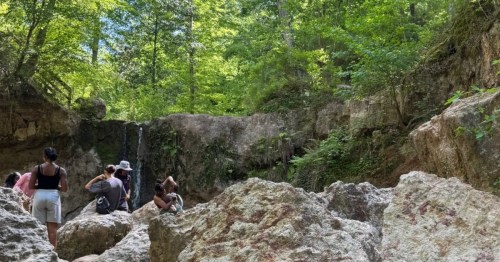 A small crowd gathers near Clark Creek Falls in Mississippi on a summer day.