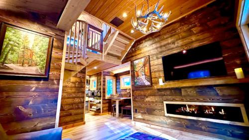 Cozy wooden cabin interior with a staircase, fireplace, artwork, and warm lighting.