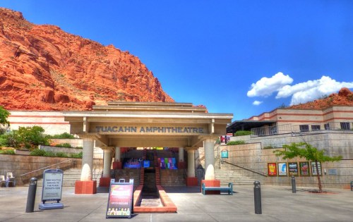Entrance to Tuacahn Amphitheatre with red rock formations in the background and a clear blue sky.