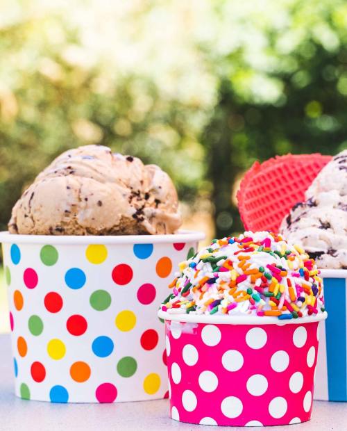 Three colorful ice cream cups: one with chocolate chip, one with sprinkles, and one with a red waffle cone.