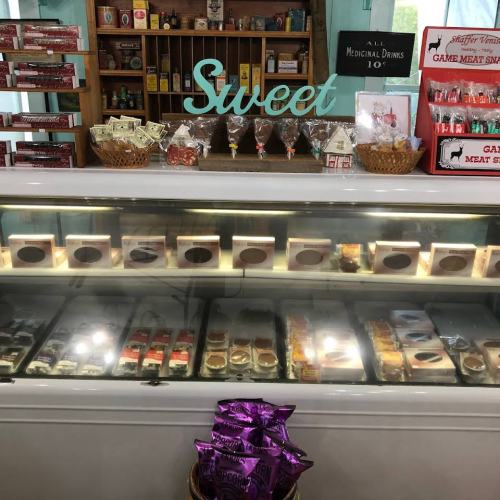 A display of sweets and snacks in a shop, featuring candy jars, meat snacks, and a glass case of treats.