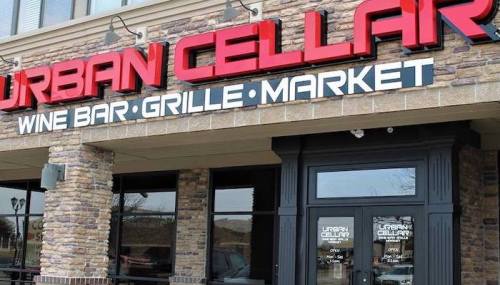 Sign for Urban Cellar, featuring a wine bar, grille, and market, with a stone facade and large red lettering.