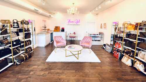 A stylish boutique interior featuring shelves of designer handbags, a pink seating area, and a chic decor.