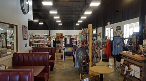 Interior of a shop featuring seating, shelves of merchandise, and a cozy atmosphere with bright lighting.