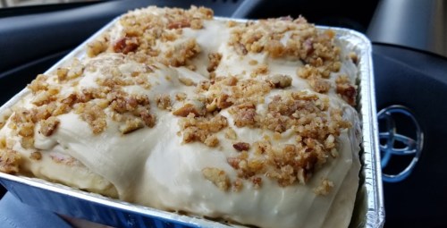 A tray of freshly baked cinnamon rolls topped with crushed nuts, sitting in a car.