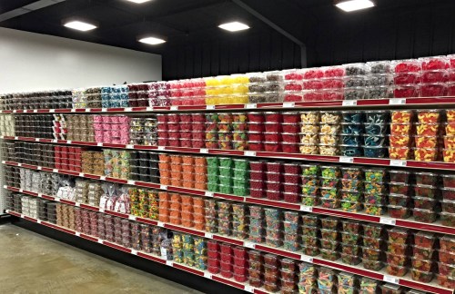 A colorful display of various candy jars neatly arranged on shelves in a store.