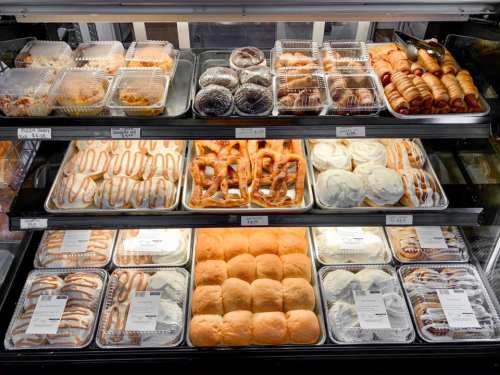 A display case filled with various baked goods, including pastries, donuts, and sweet rolls.