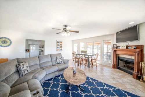 Cozy living room with a sectional sofa, coffee table, and dining area, featuring a fireplace and large windows.