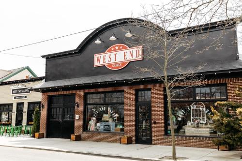 Exterior of a building with a sign reading "West End" and large windows, surrounded by trees and other shops.