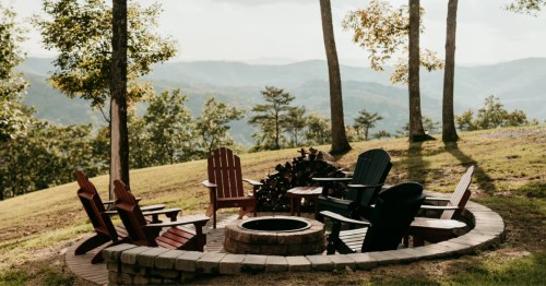 A luxury cabin in West Virginia with a fire pit and chairs overlooking the mountains.