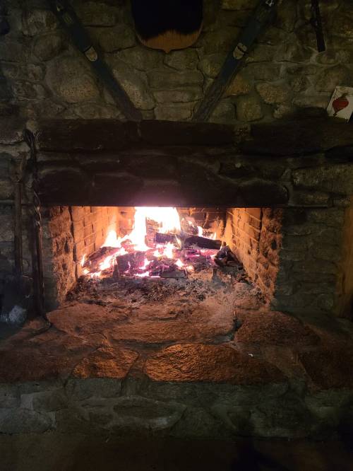 A cozy stone fireplace with glowing embers and flames, creating a warm atmosphere.