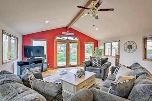 Cozy living room with a red accent wall, large windows, a TV, and comfortable seating around a coffee table.