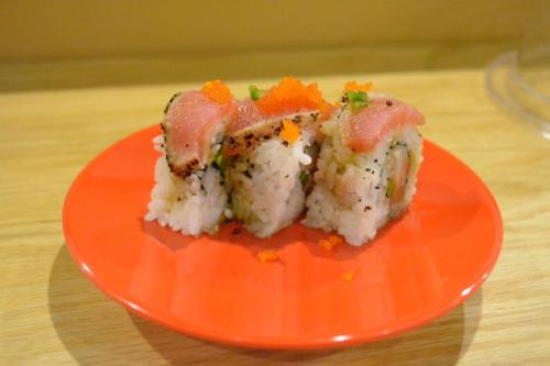 Three pieces of sushi on a red plate, topped with tuna, green onions, and orange fish roe.