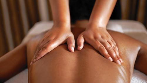 A person receiving a massage, with hands gently applying pressure on their back.
