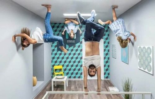 A playful room with people appearing to hang upside down from the ceiling, creating an optical illusion.