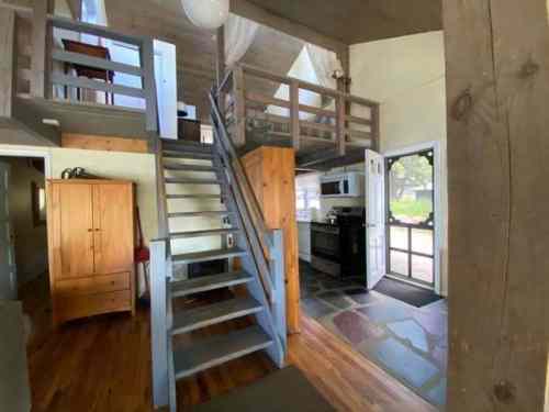 Cozy interior of a two-story home featuring a staircase, kitchen, and large windows for natural light.