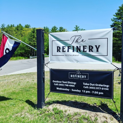 Sign for "The Refinery" restaurant and market, featuring outdoor dining and takeout information.