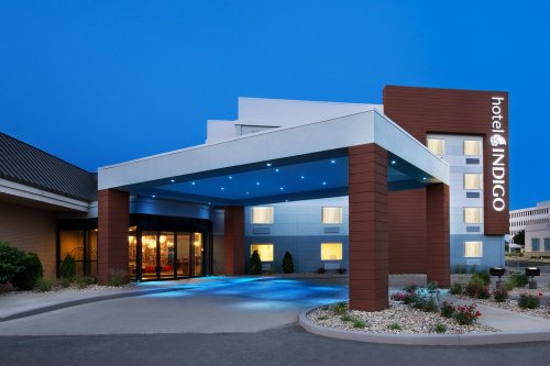 Exterior view of Hotel Indigo at dusk, featuring a modern entrance and illuminated signage.