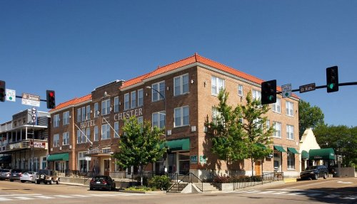 Historic Hotel Chester building with a red-tiled roof, green awnings, and traffic lights in front. Clear blue sky.