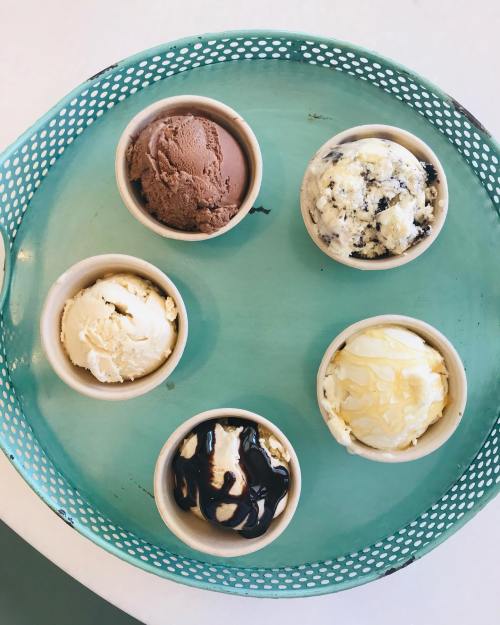 A teal tray holds five small cups of different ice cream flavors, including chocolate, vanilla, and cookies and cream.