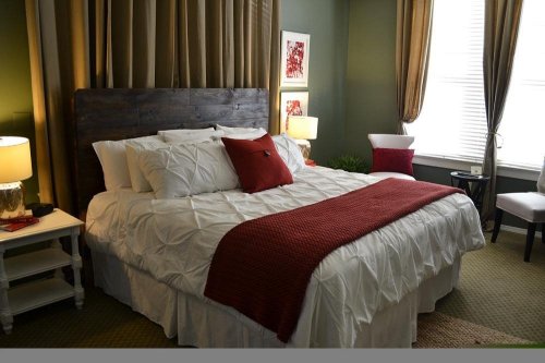 Cozy bedroom featuring a large bed with white linens, red accents, and warm lighting from bedside lamps.