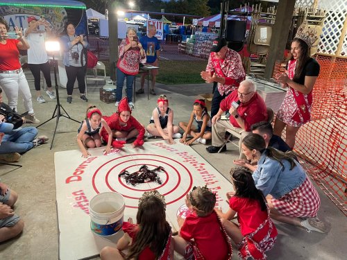 A lively event with participants in red outfits gathered around a large circle on the ground, engaging in a game or activity.